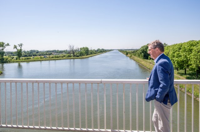 Wethouder Hub Meuwissen op een brug uitkijkend over het water