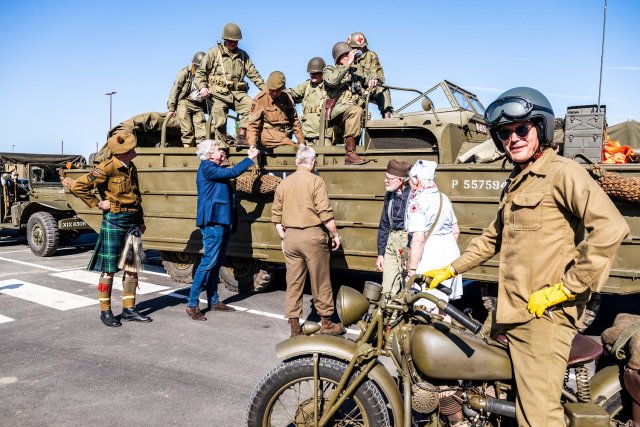 Wethouder Peter Pustjens schudt een deelnemer aan de liberty tour, die op een militair amfibievoertuig staat, de hand.