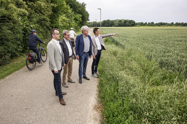 4 heren staren over het veld waar de bouw zal worden gerealiseerd