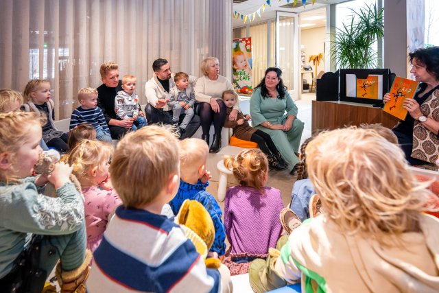 Wethouder Inge Minkenberg en 19 peuters in een kring tijdens een voorleesmoment