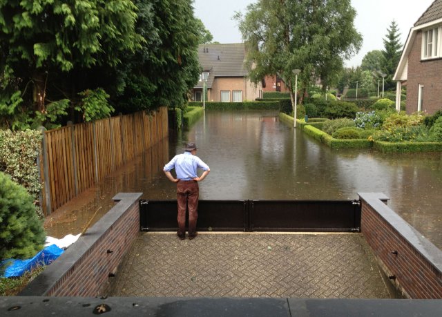 Man bij waterkering bij zijn aflopende oprit