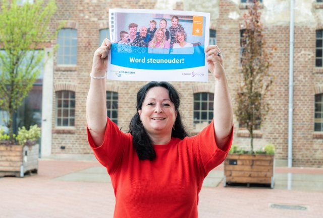 Wethouder Inge Minkenberg houdt een poster omhoog met de tekst "Word steunouder"