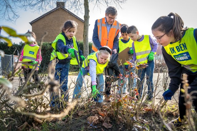 Wethouder Hub Meuwissen ruimt, samen met enkele leerlingen van basisschool Patricius, zwerfafval op