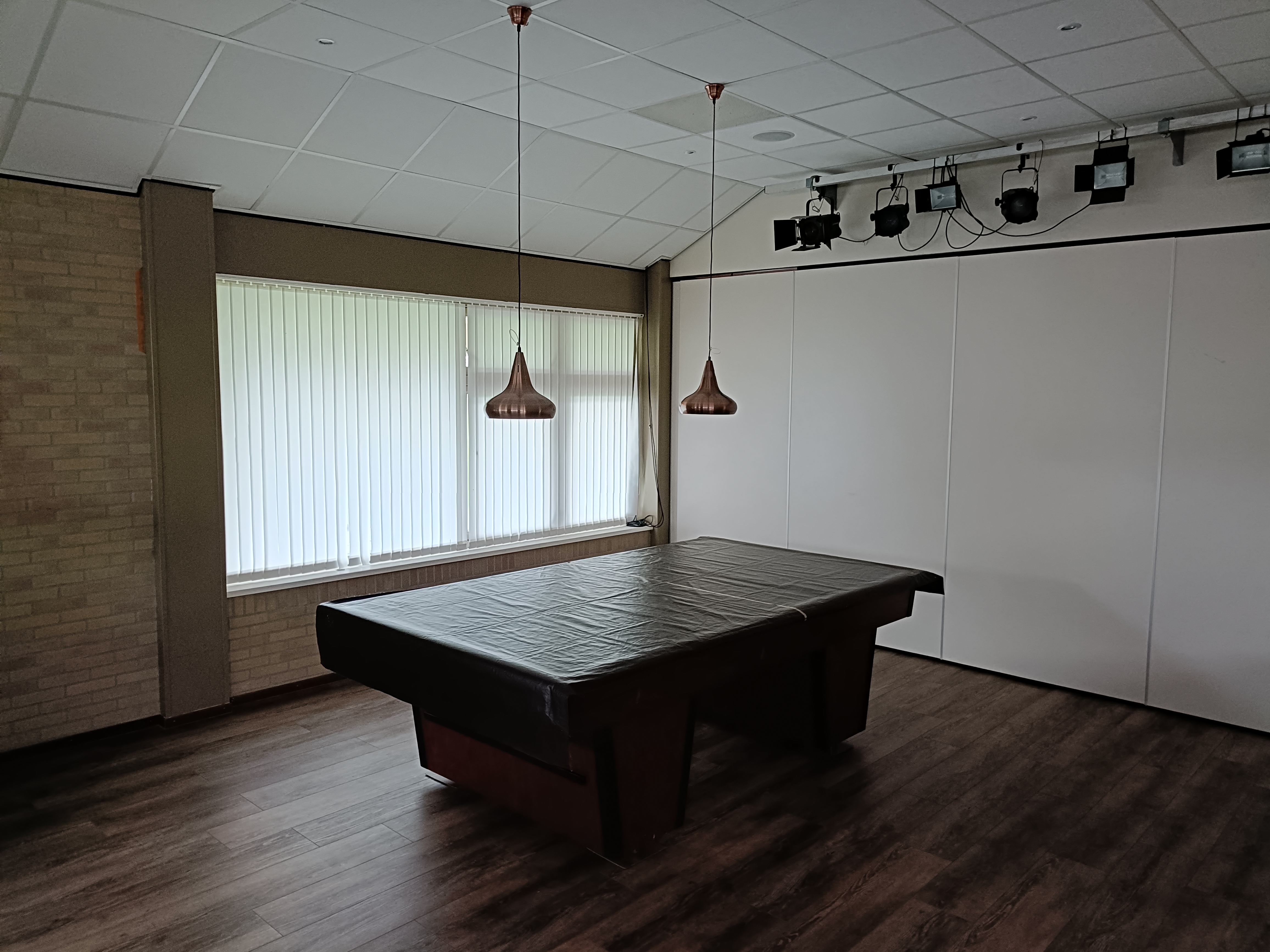 Een biljarttafel in het dorpshuis met een kleed er over heen.