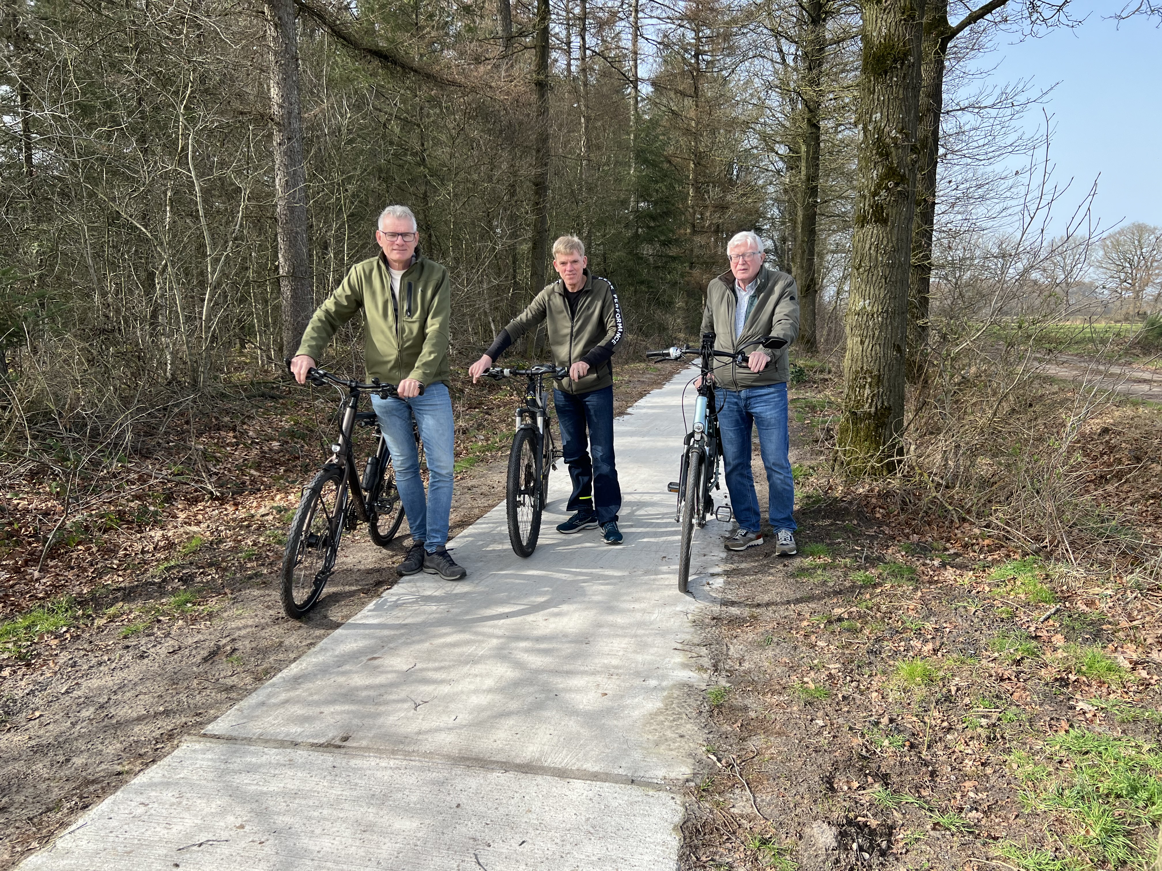 Drie personen met een fiets aan de hand staan op het nieuwe verharde fietspad.