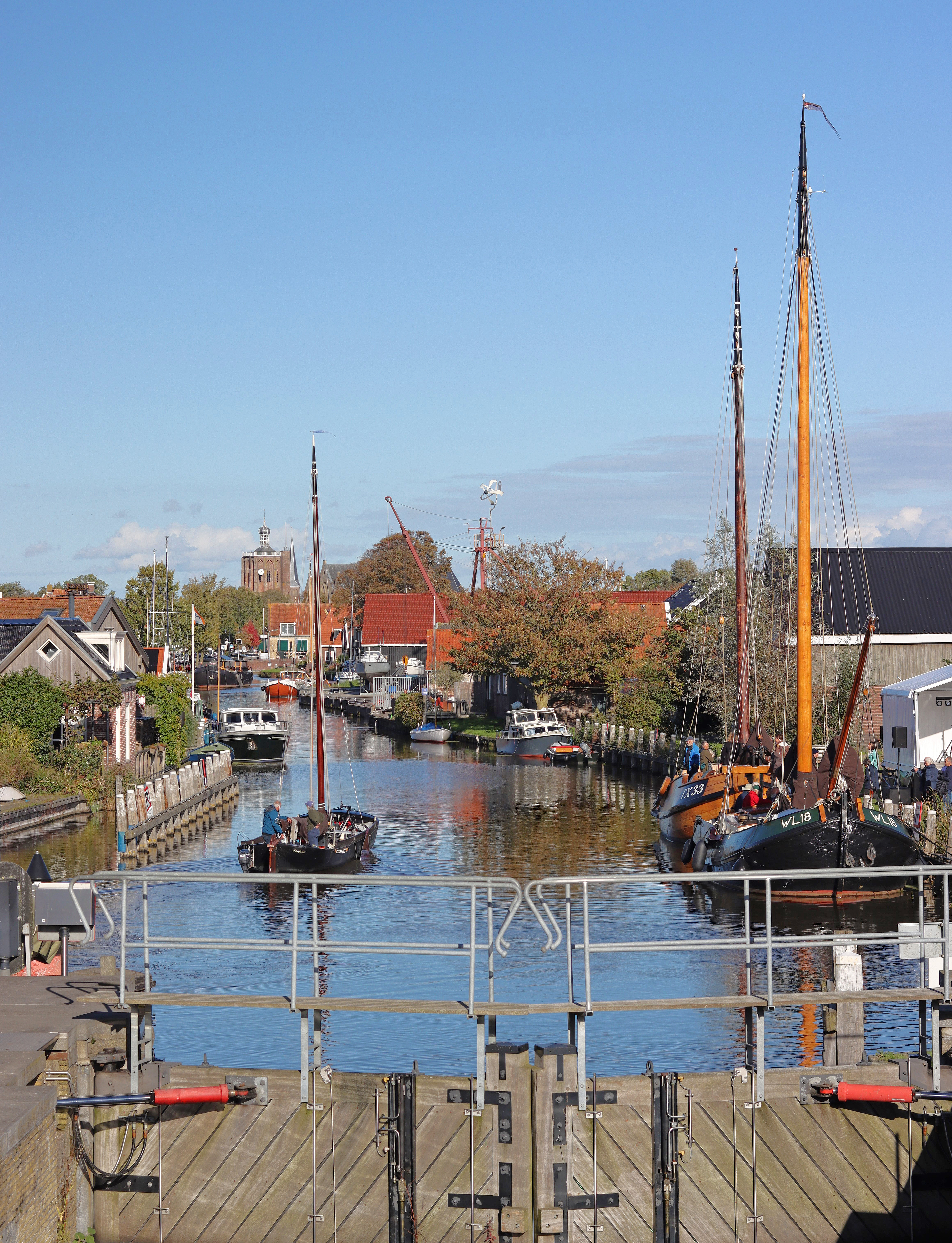 Kleine sluis in Harlingen waar boten langs de walkant liggen.