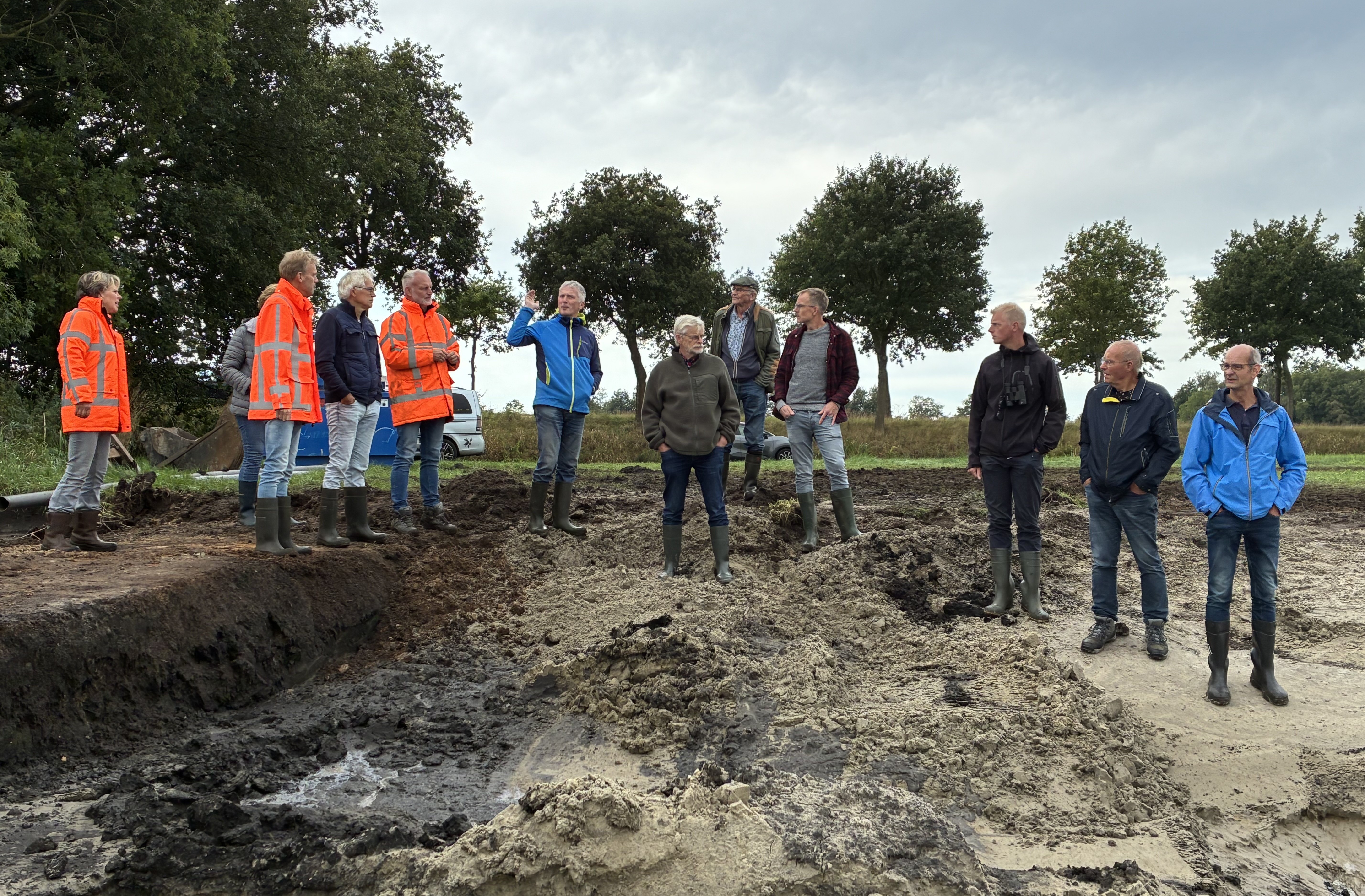 Alle leden van de gebietscommissie staan in de modder met laarzen aan.
