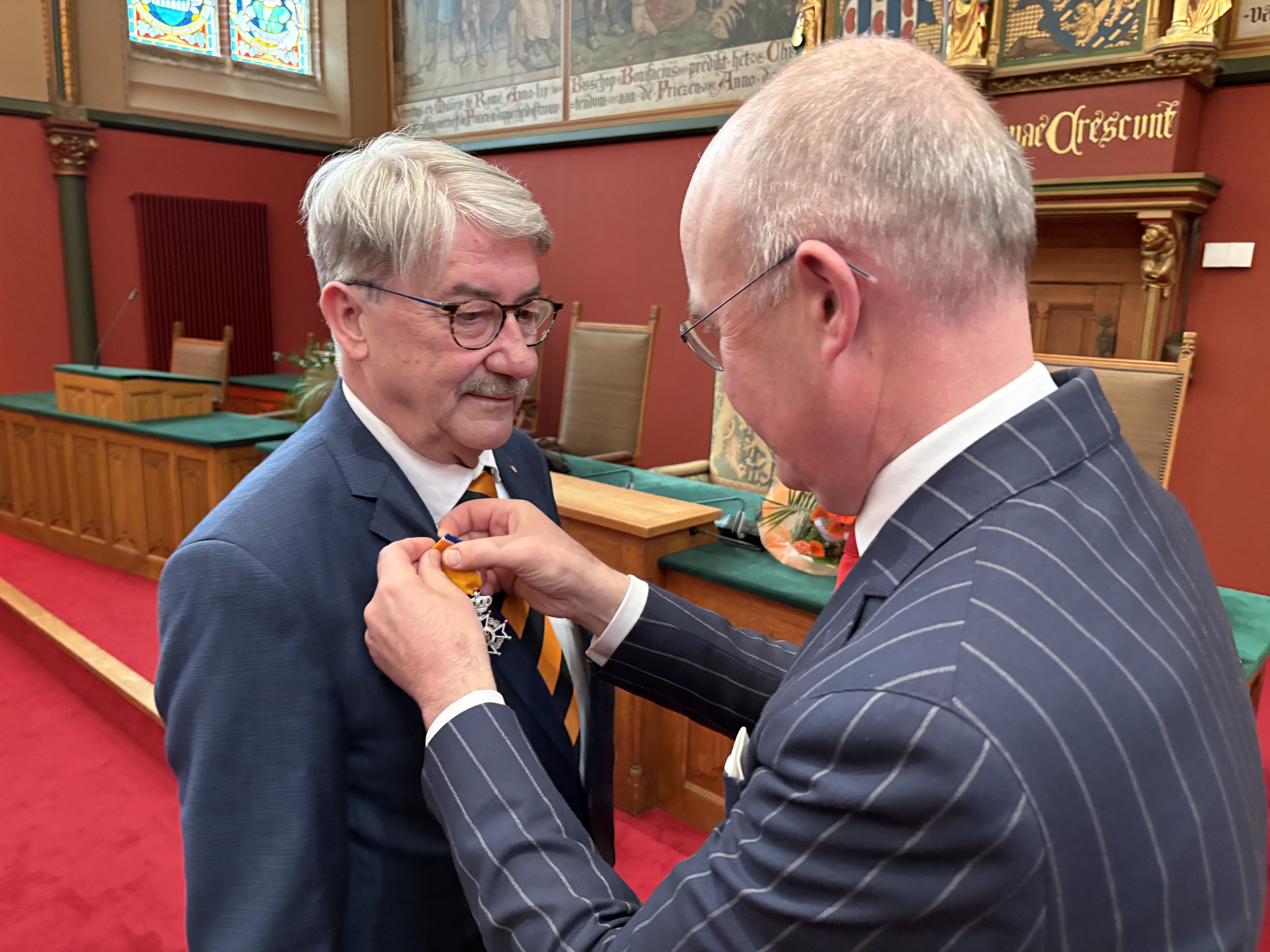 De heer Oldersma krijgt de onderscheiding opgespeld door commissaris van de Koning Brok.