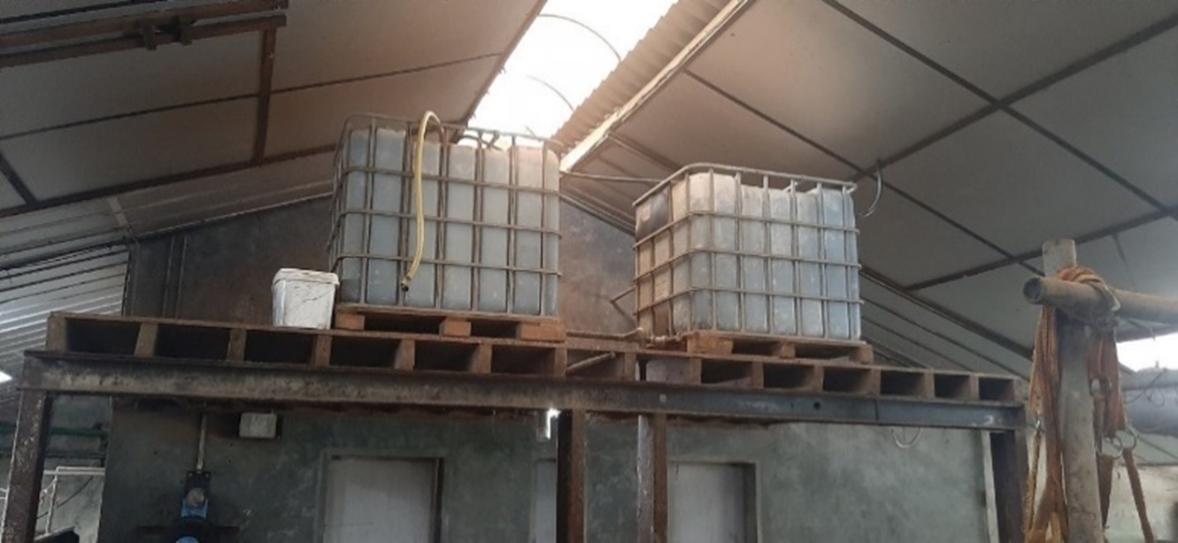 Twee watertanks in een rek in een koeienstal.