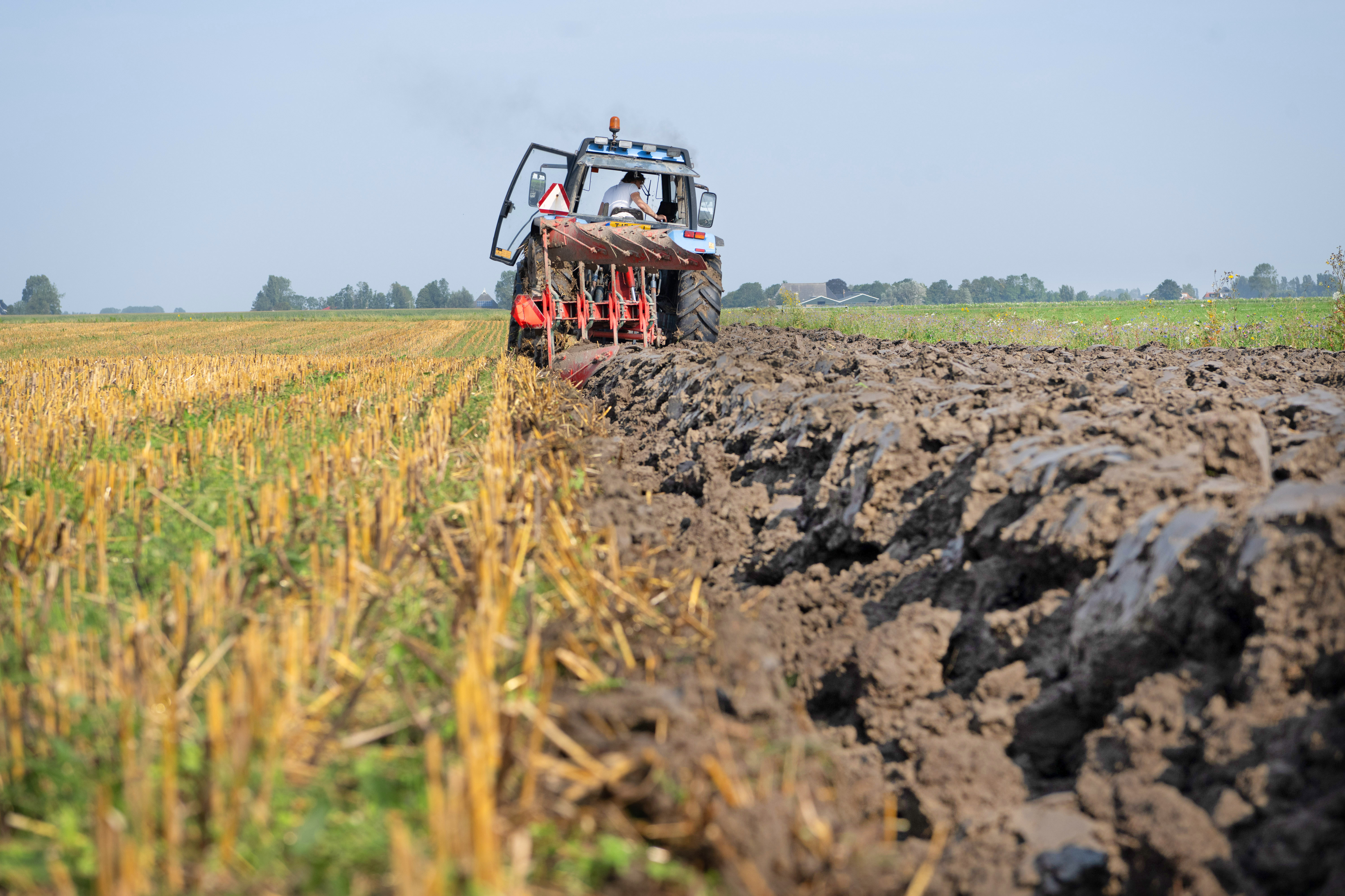 Een tractor is het weiland aan het omploegen.