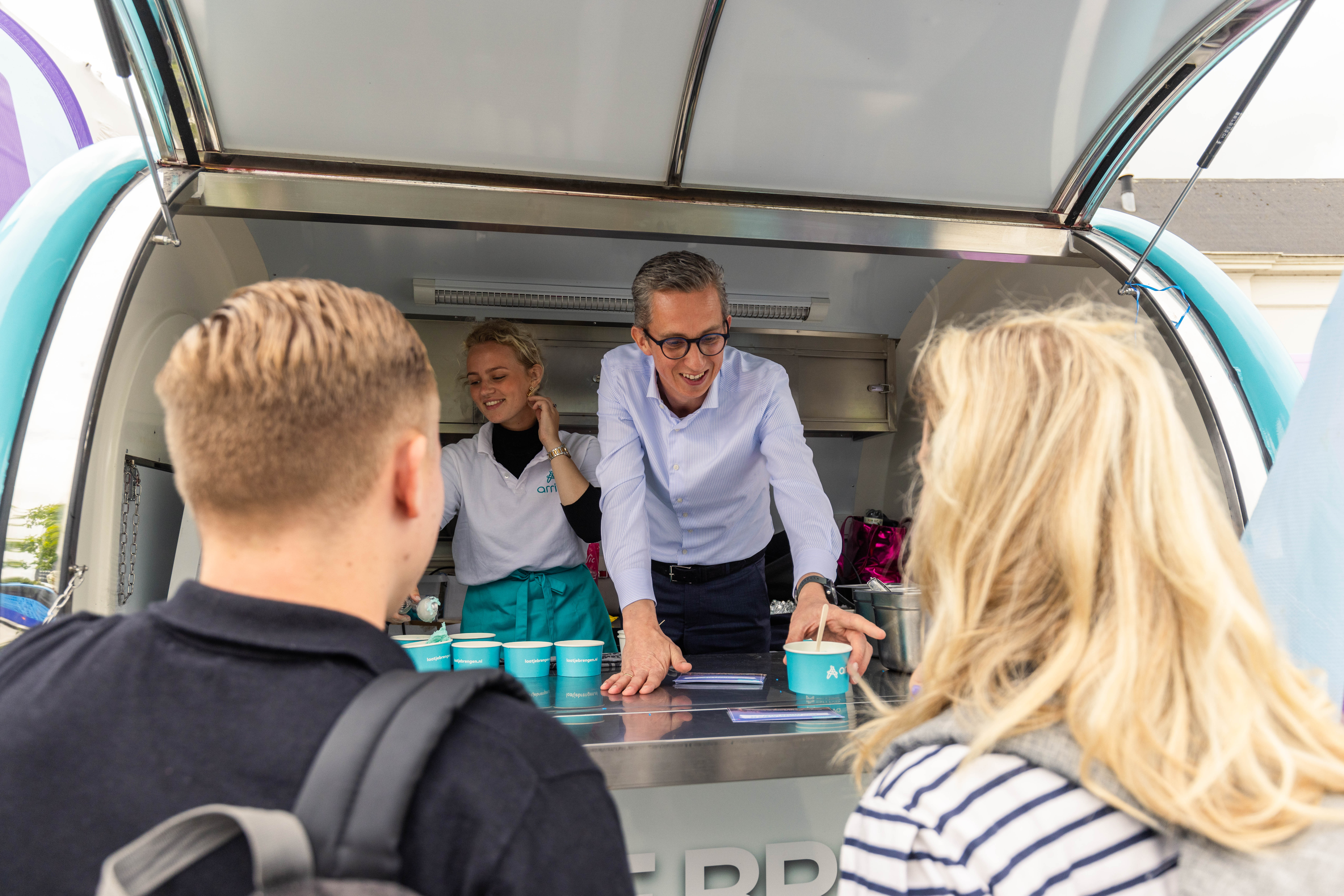 Gedeputeerde Matthijs de Vries staat ijsjes uit te delen vanuit een ijsbusje.