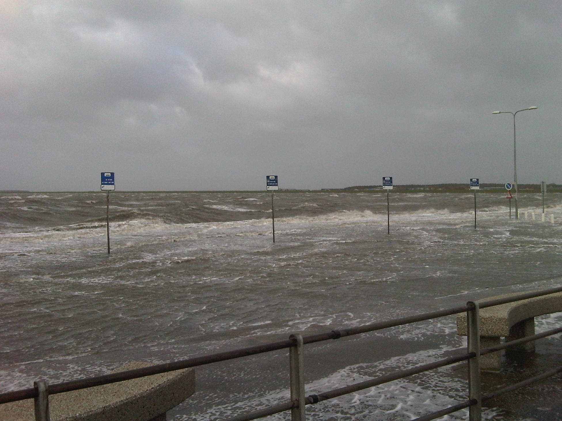 Een viertal bushaltebordjes staan op de waddenkade wat onder water staat.