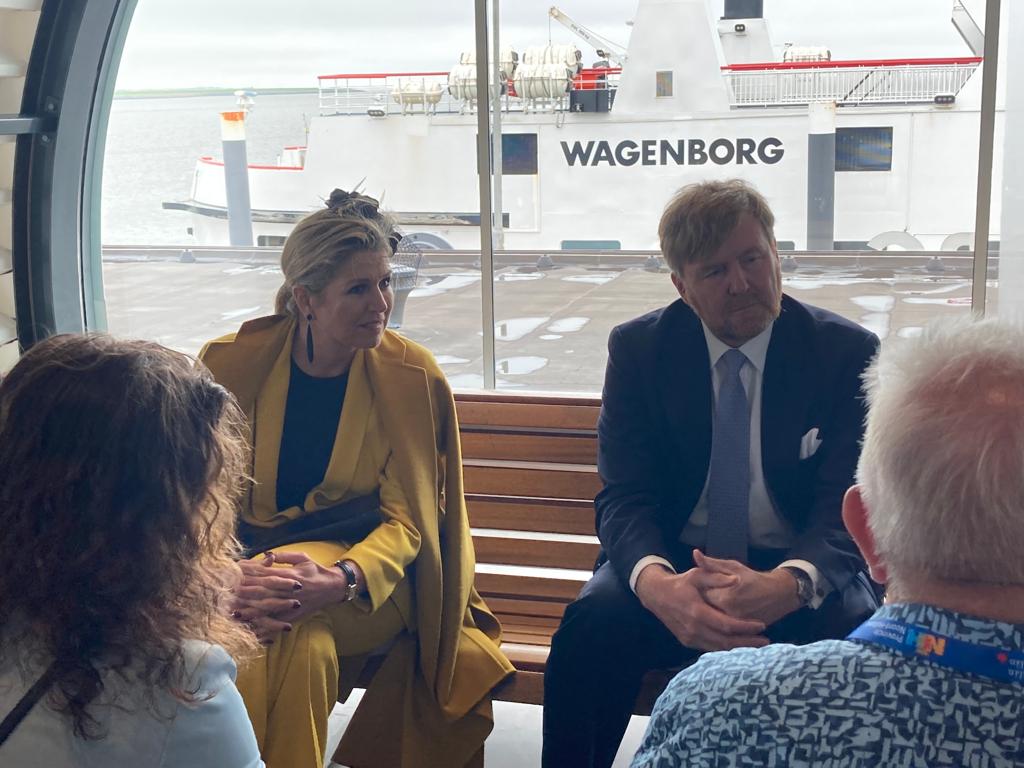 De Koning en Koningin zitten in de terminal van Wagenborg op een houten bankje