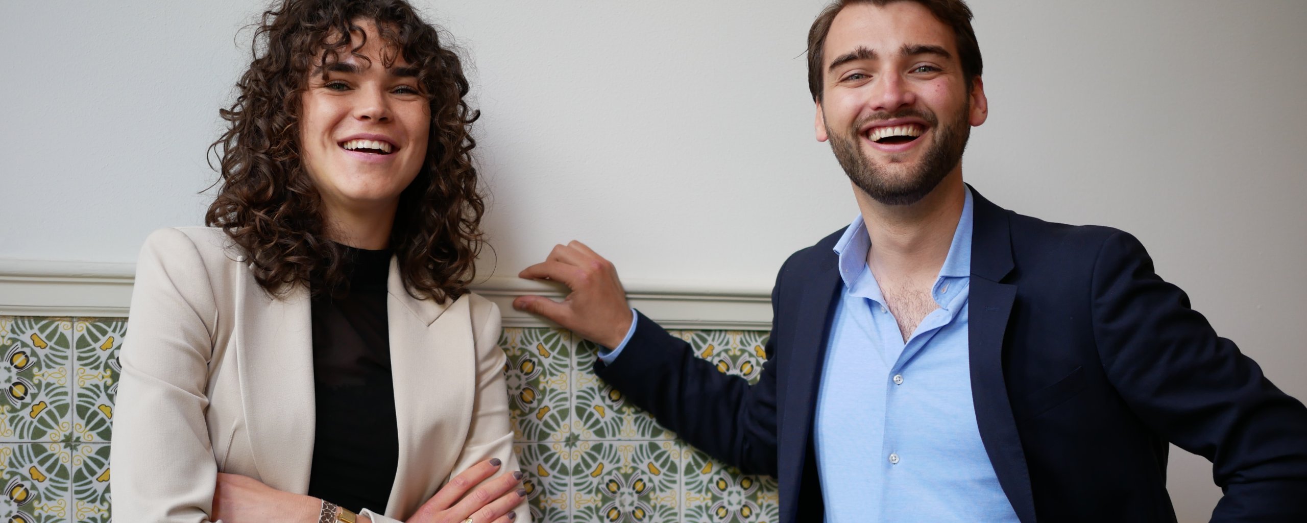 Een man en een vrouw staan lachend naast elkaar op de foto.