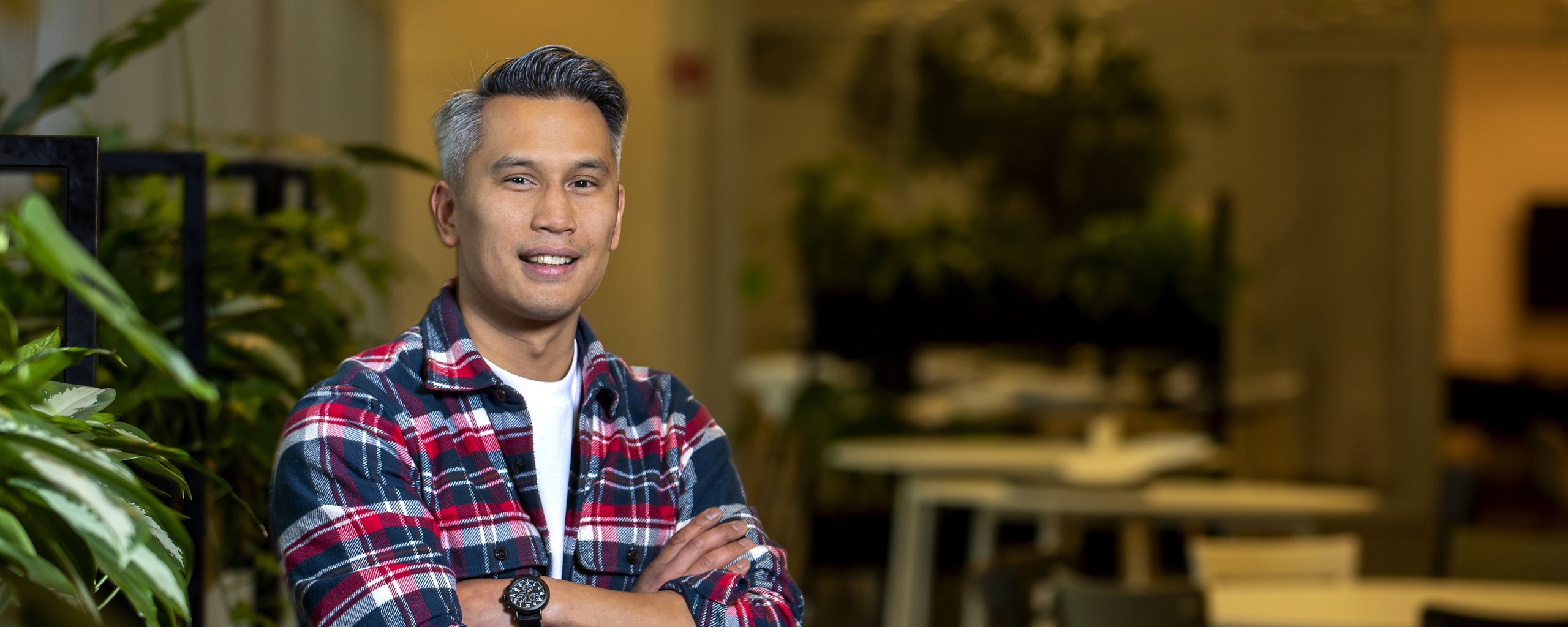 Man kijkt lachend in de camera met de met armen over elkaar.