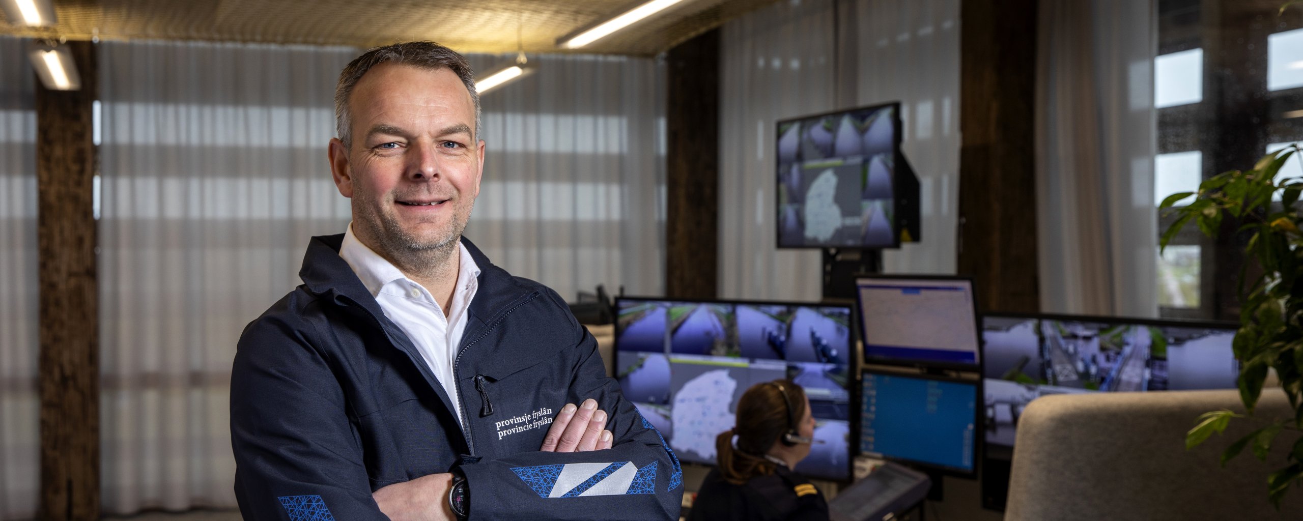 Een man staat met zijn armen over elkaar in de ruimte waar de bruggen op afstand bediend worden.