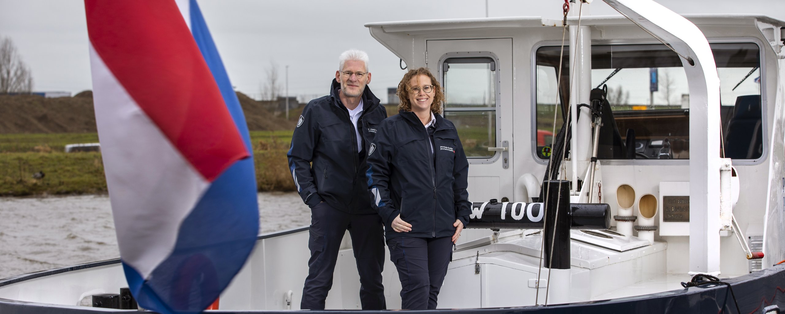 Man en vrouw op een boot. De Nederlandse vlag is ook te zien.