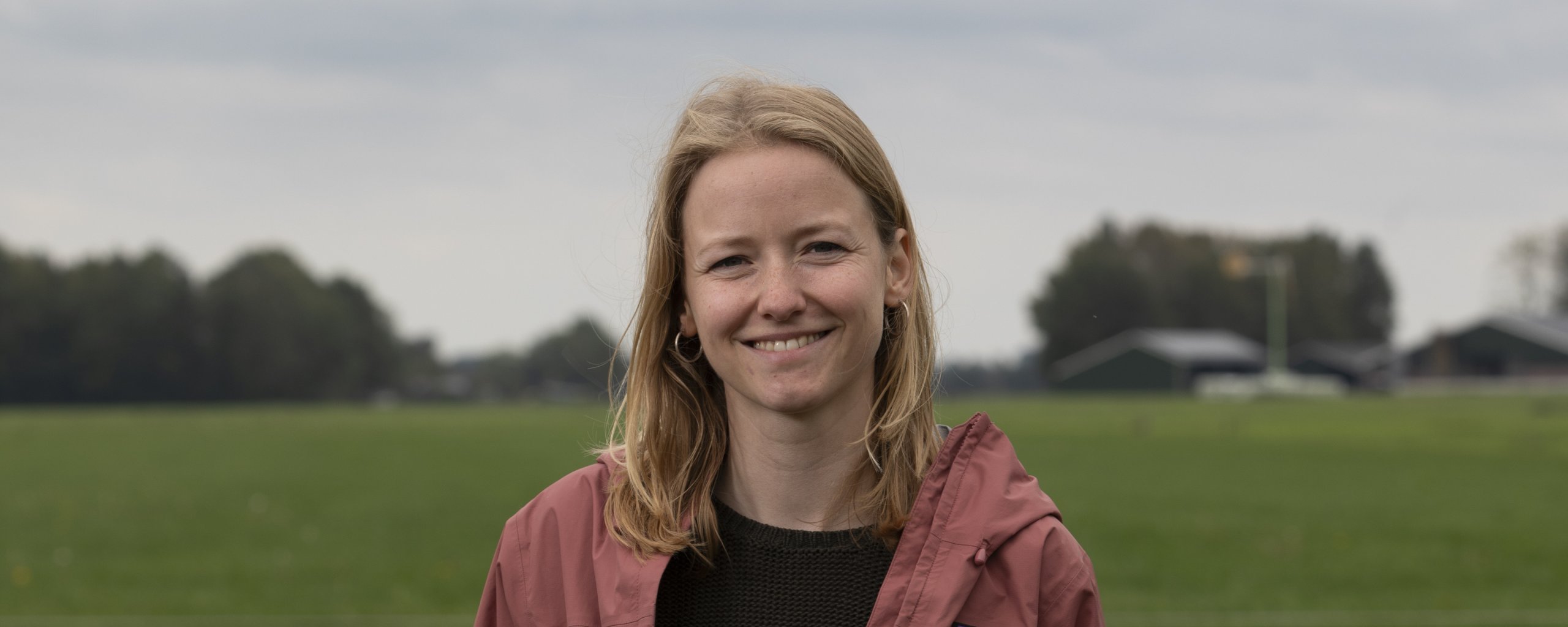Een vrouw staat voor een weiland