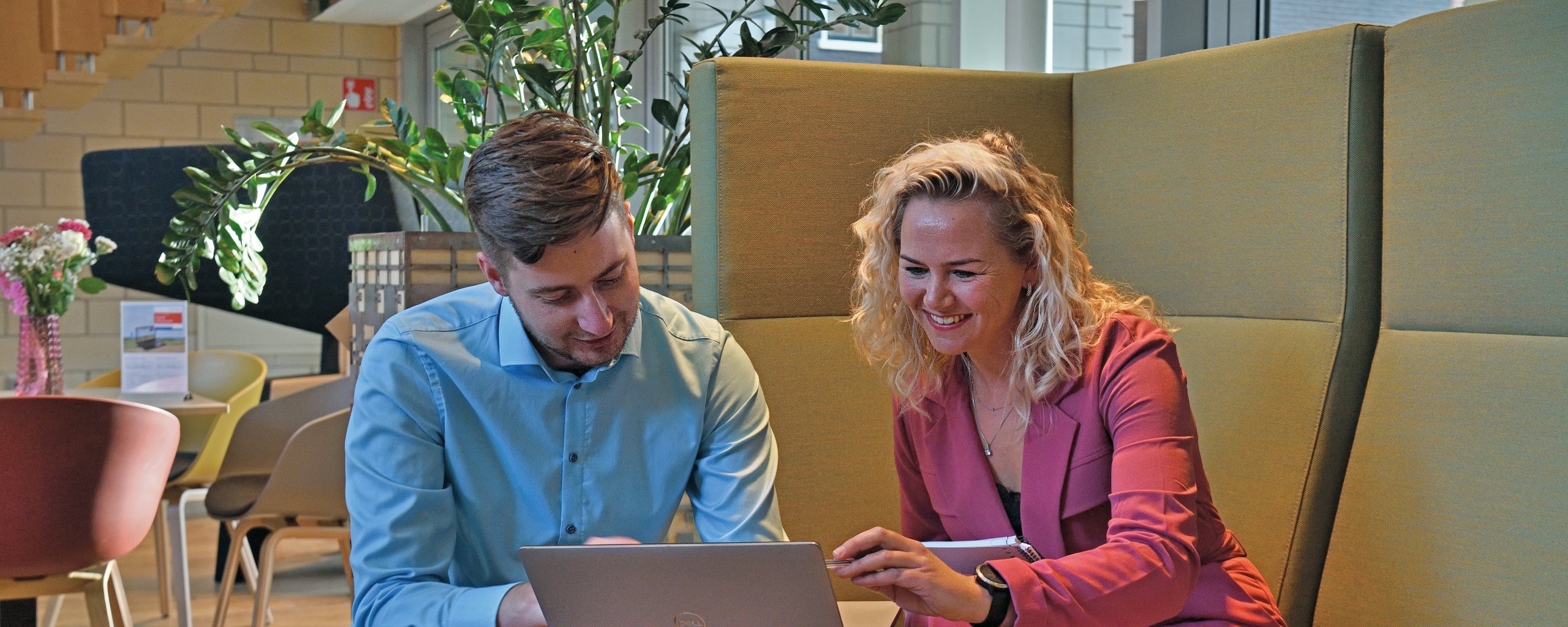 Twee personen zitten op een bank met de laptop open.