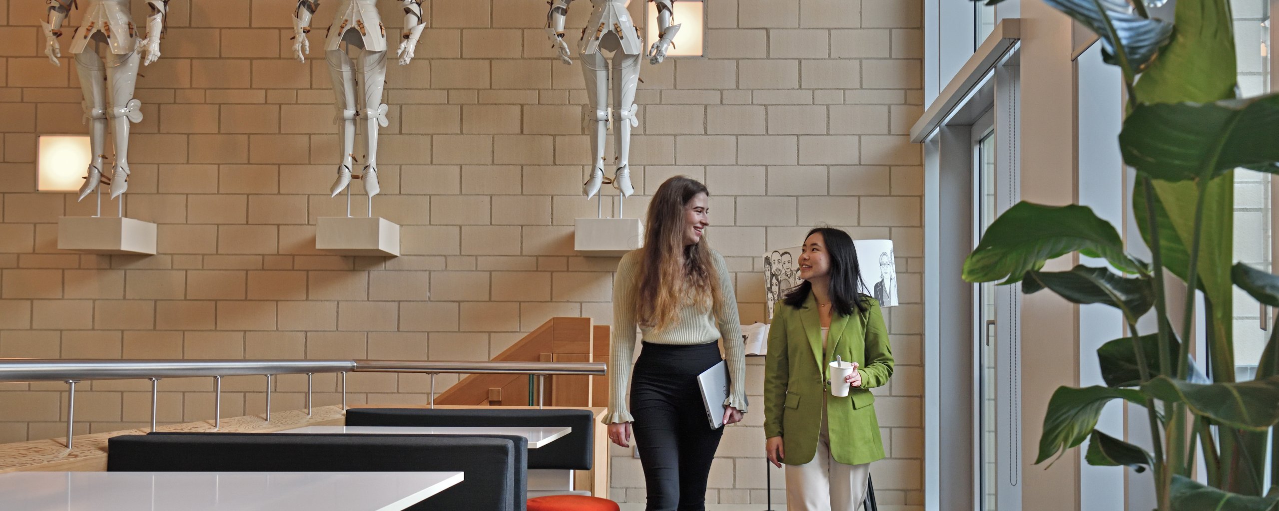 Twee vrouwen lopen naast elkaar in de publiekshal van het provinciehuis.
