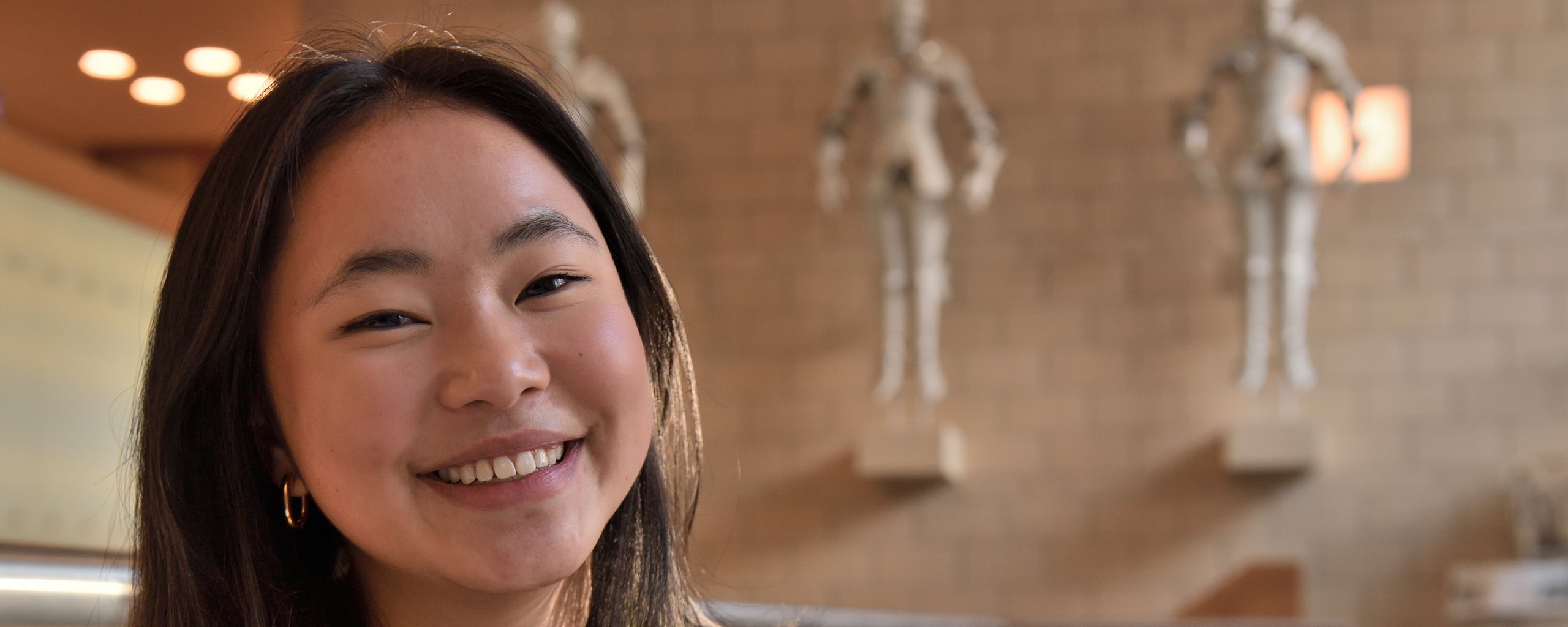 Een lachende vrouw zit in de publiekshal van het provinciehuis.