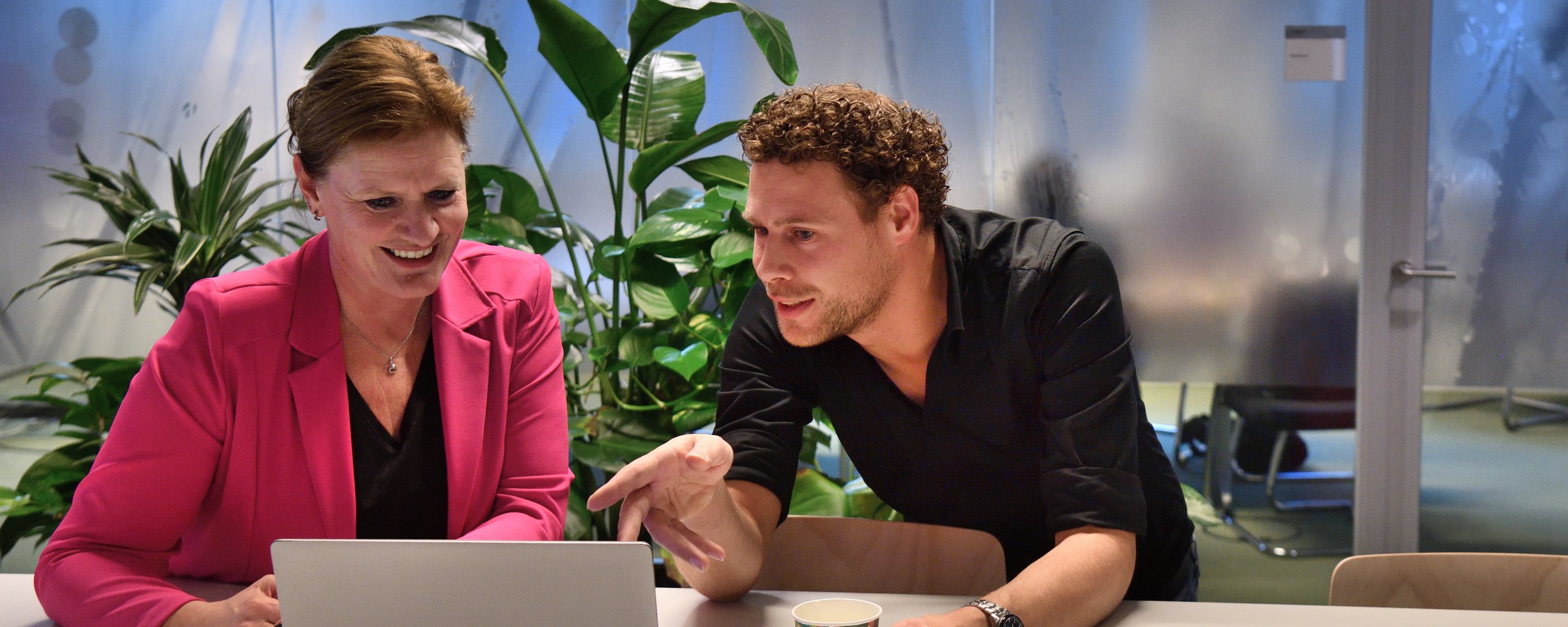 Een man en vrouw zitten voor een laptop. De man wijst naar het scherm
