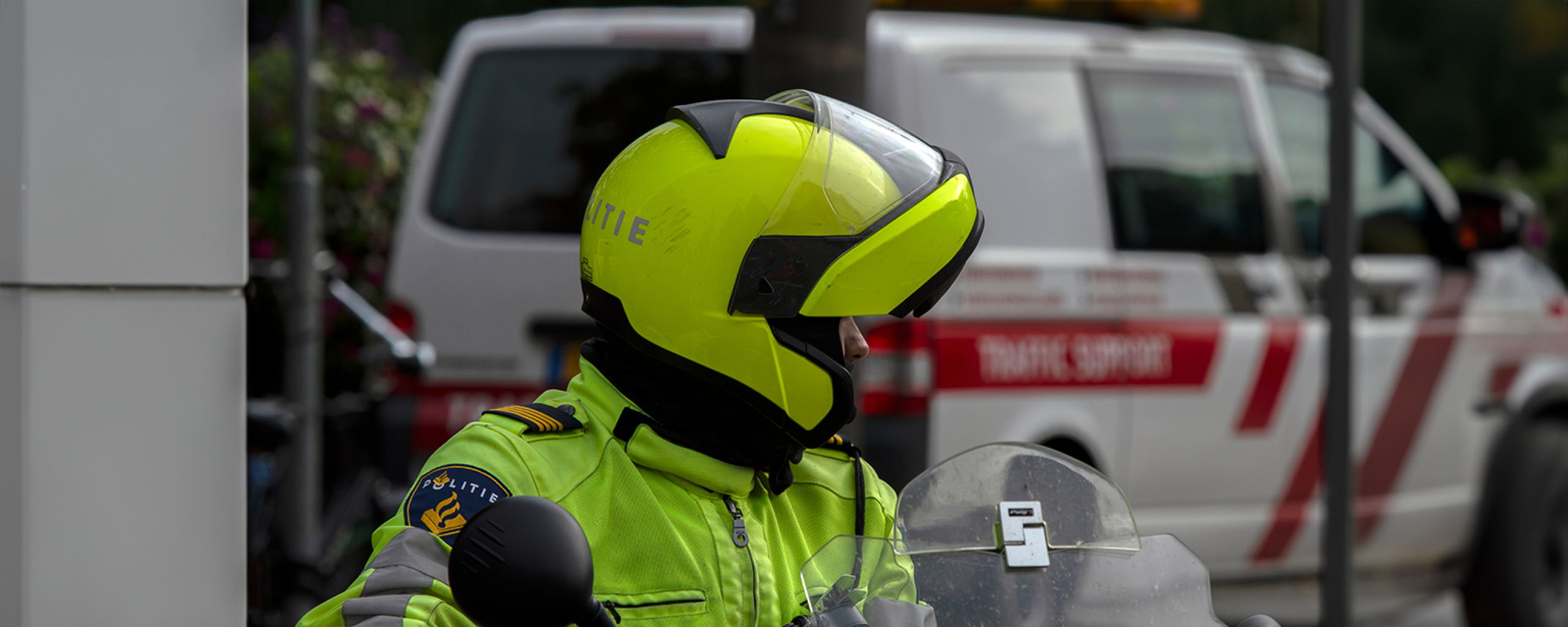 Een politieagent op de motor en gele helm op kijkt achterom