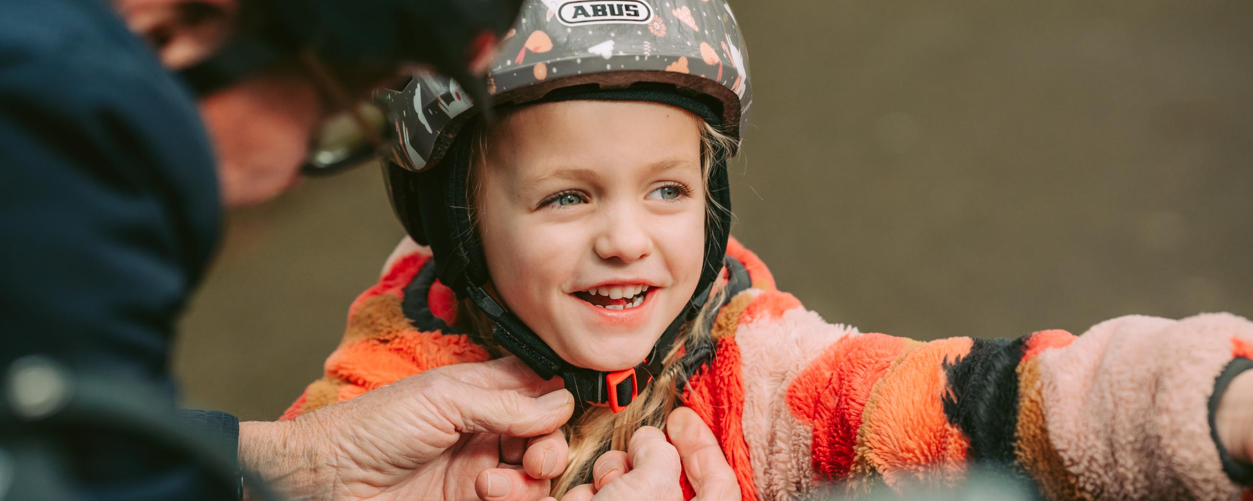 Opa doet de helm vast van zijn kleindochter