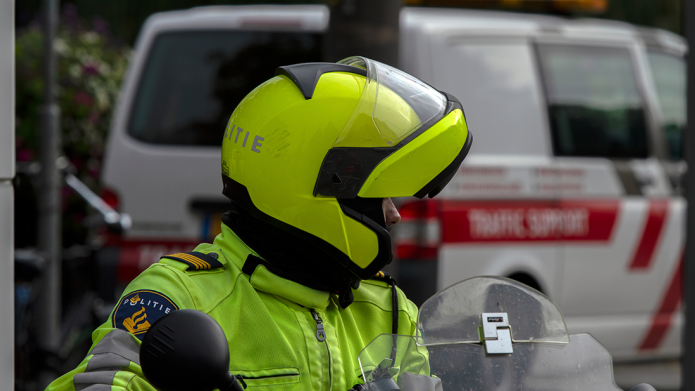 Een politieagent op de motor en gele helm op kijkt achterom