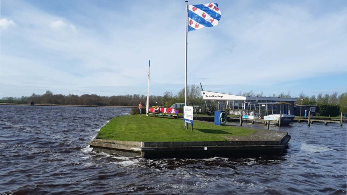 Foto van Jachthaven de Trijesprong met Friese vlag en mensen bij bankje