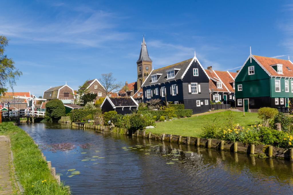 Een aantal huizen en een kerkje met op de voorgrond een sloot en helemaal links achterin nog een klapbrugje.