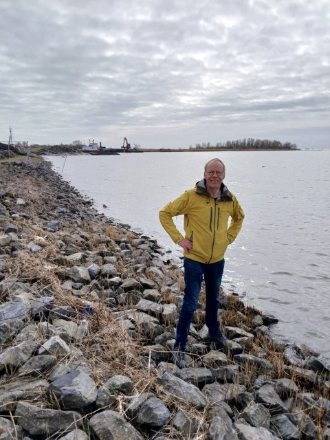Henk Miedema staat op de rotsen naast het water.