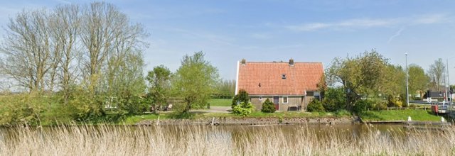 Een huis aan het water, omgeven door gras