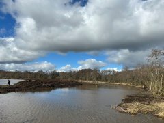 Landschap met op de voorgrond water en dikke wolken in de lucht.