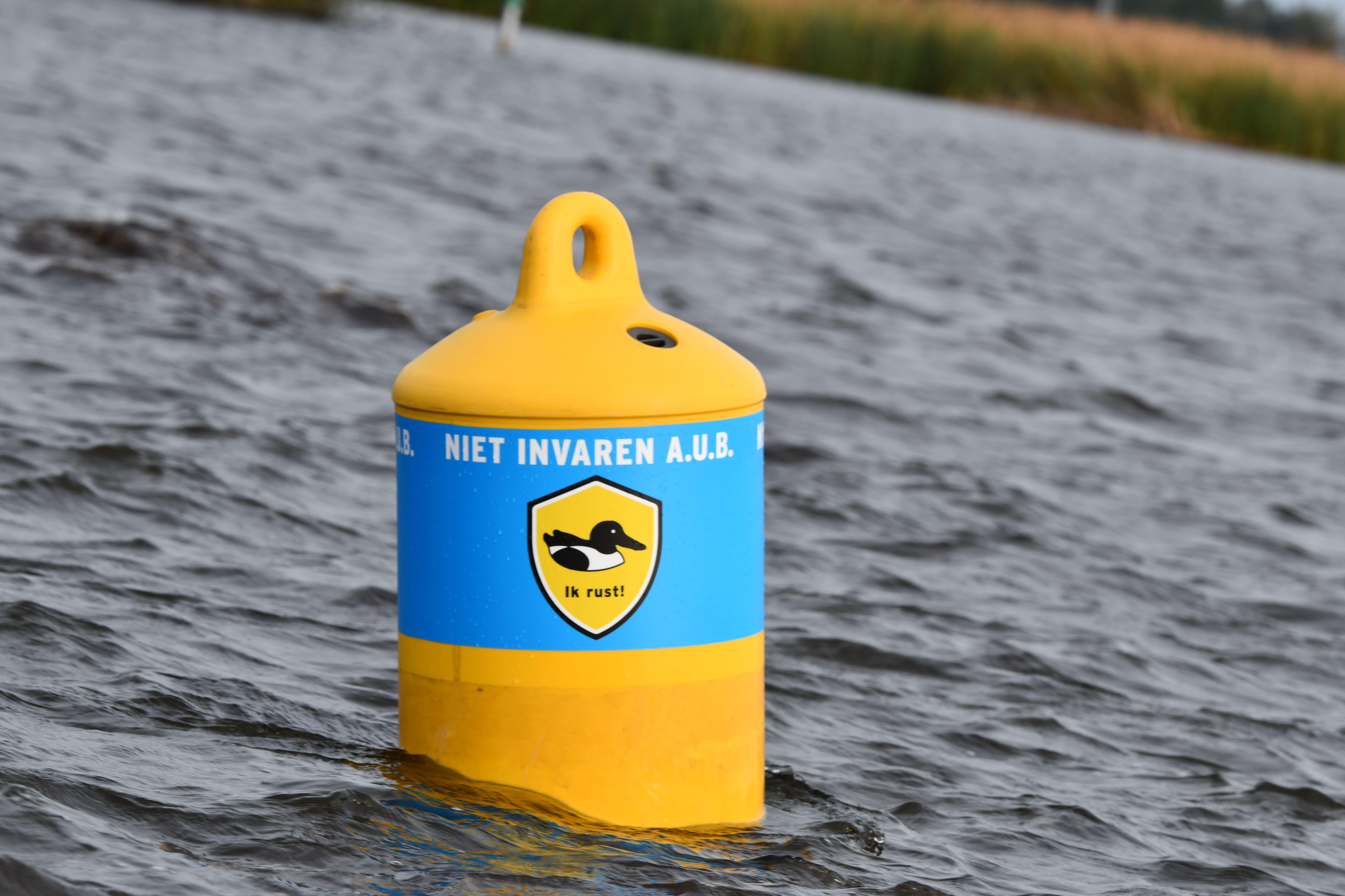 Een gele boei in het water waarop staat; Niet invaren a.u.b. Een afbeelding van een vogel met daaronder; ik rust!