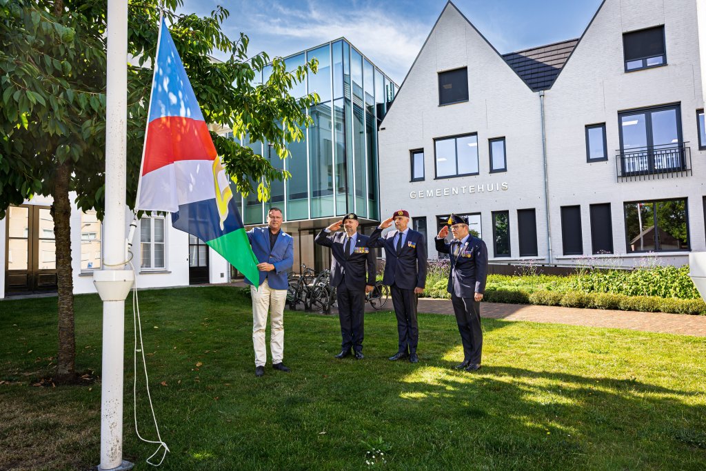 Mayor Van Bree raises the veterans' flag while three veterans salute 