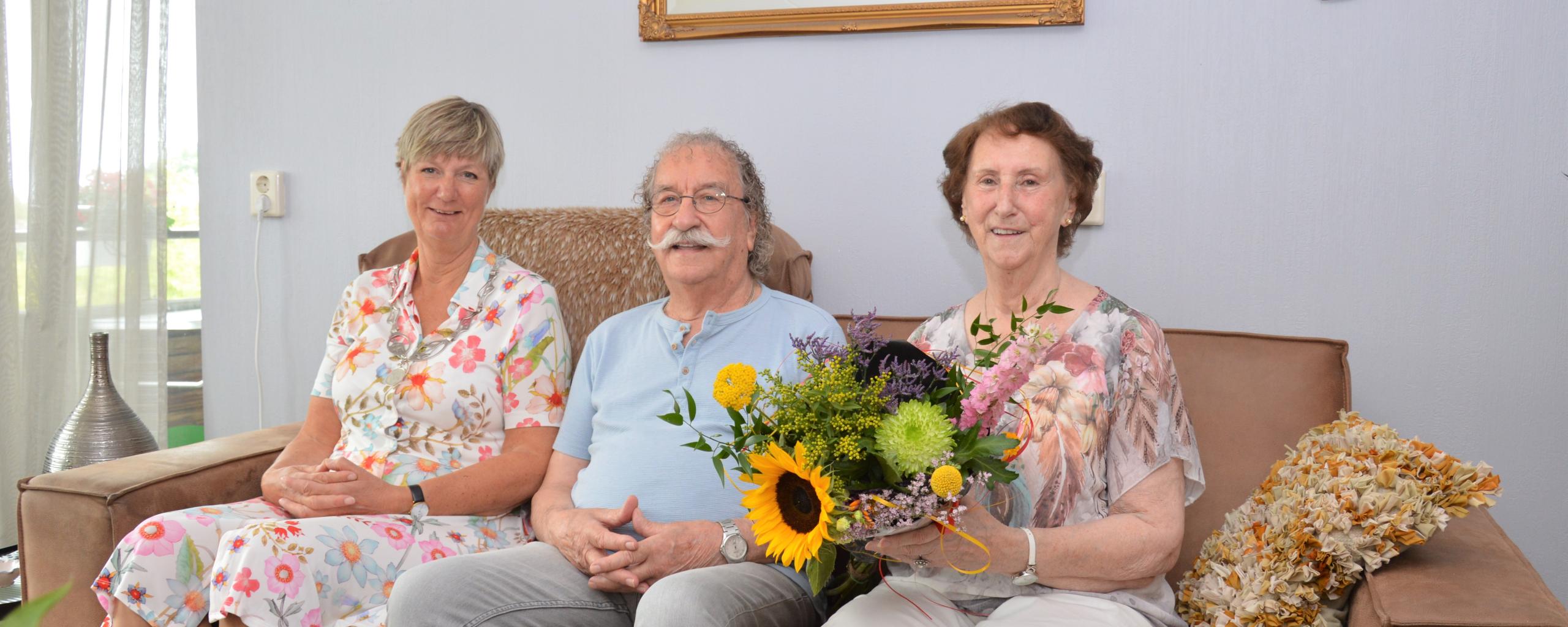 Op de bank zit de burgemeester met het echtpaar dat 60 jaar getrouwd is.