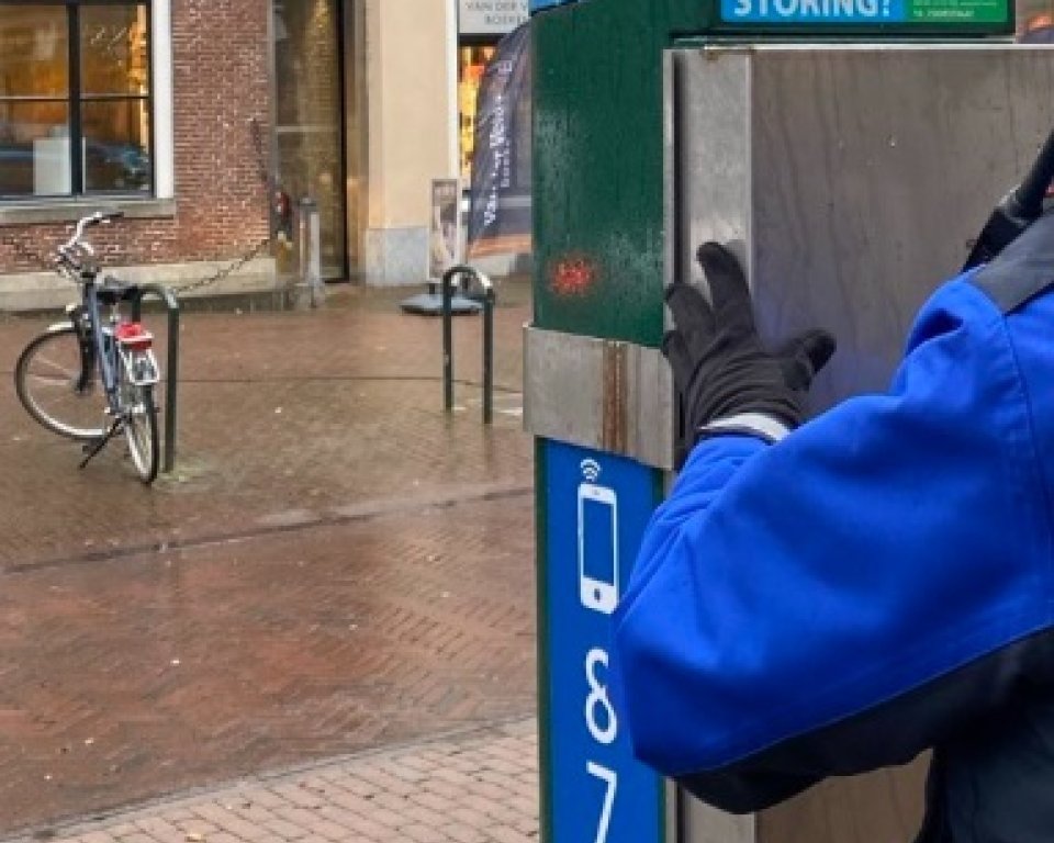 Afbeelding waarop te zien is hoe een kap op een parkeerautomaat geplaatst word.