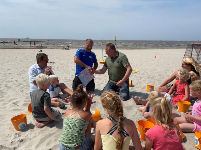 Wethouder Sijtsma lanceert de beweeg- en speelkaart aan Stijn Kooijman op het Harlinger strand