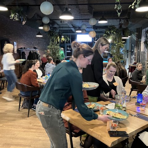 Zwangere vrouwen zitten gezellig aan een tafel tijdens het Fit4Two diner in 't Perron, Heeze, genietend van een driegangendiner. 