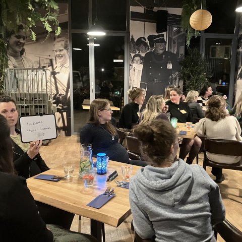 Zwangere vrouwen zitten gezellig aan een tafel tijdens het Fit4Two diner in 't Perron, Heeze, genietend van een driegangendiner. 