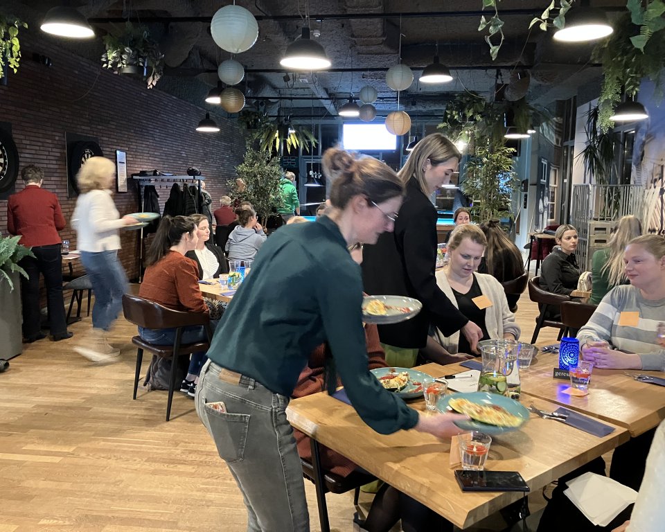 Zwangere vrouwen zitten gezellig aan een tafel tijdens het Fit4Two diner in 't Perron, Heeze, genietend van een driegangendiner. 