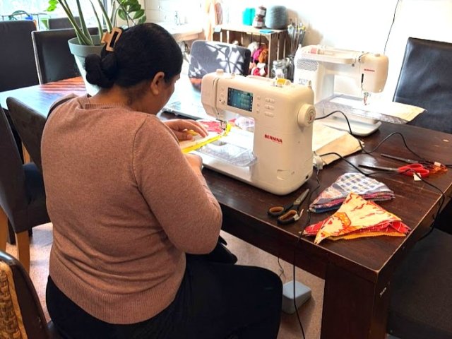 Vrouw achter een naaimachine, tijdens een naailes.