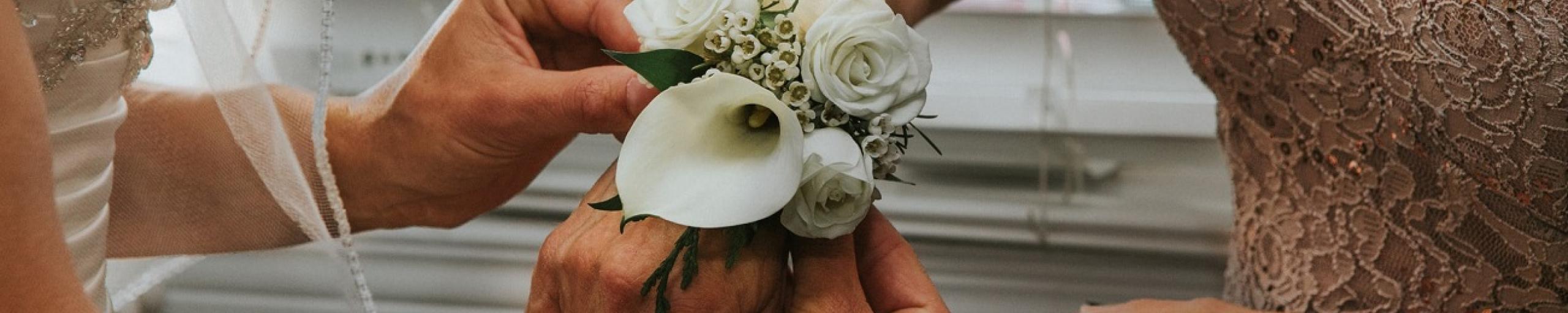 bruid schikt bloemenarmband bij andere bruid