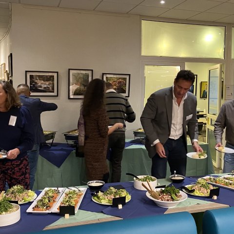 Mensen lopen langs een lange buffettafel met een bord in de handen