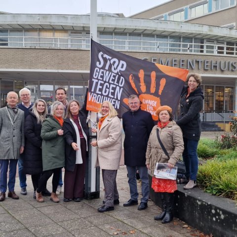 Het voltallige college staat voor het gemeentehuis, naast de vlaggenmast met daarin vlag van Orange the World.