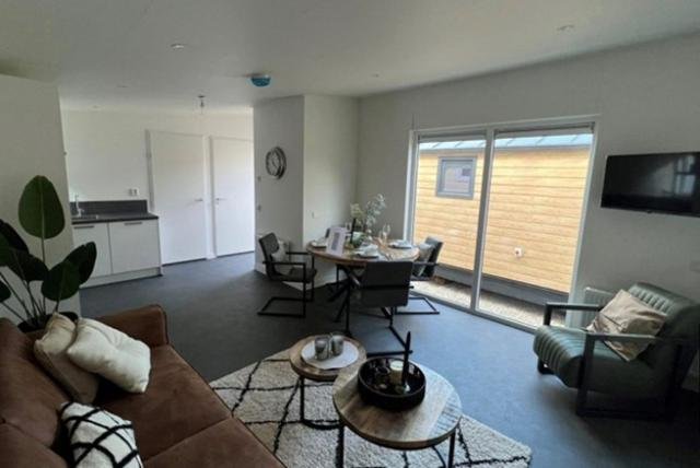 Woonkamer met een bank, koffietafel, loungestoelen en planten