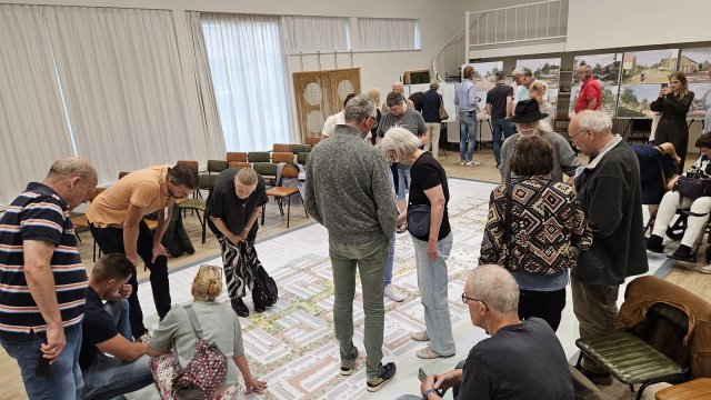 Bewoners lopen over de enorme kaart van het voorlopig ontwerp van de wijk Stad en Lande in Huizen.
