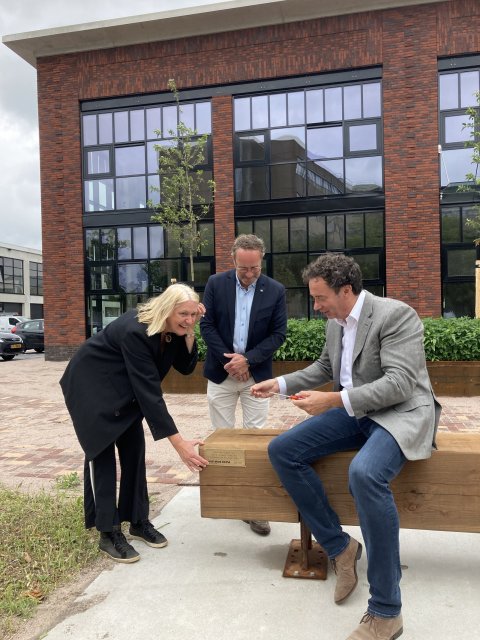 Wethouders Van Werven en Boom en projectmanager Peter van Dijk van Herkon bij het gesponsorde bankje aan de Havenstraat in Huizen.