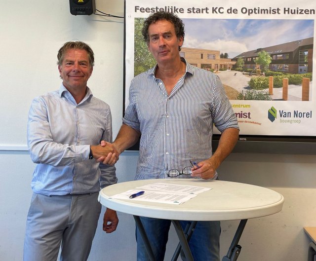 De wethouder schudt de hand van Hans van Norel, terwijl ze bij een tafel staan met ondertekende documenten